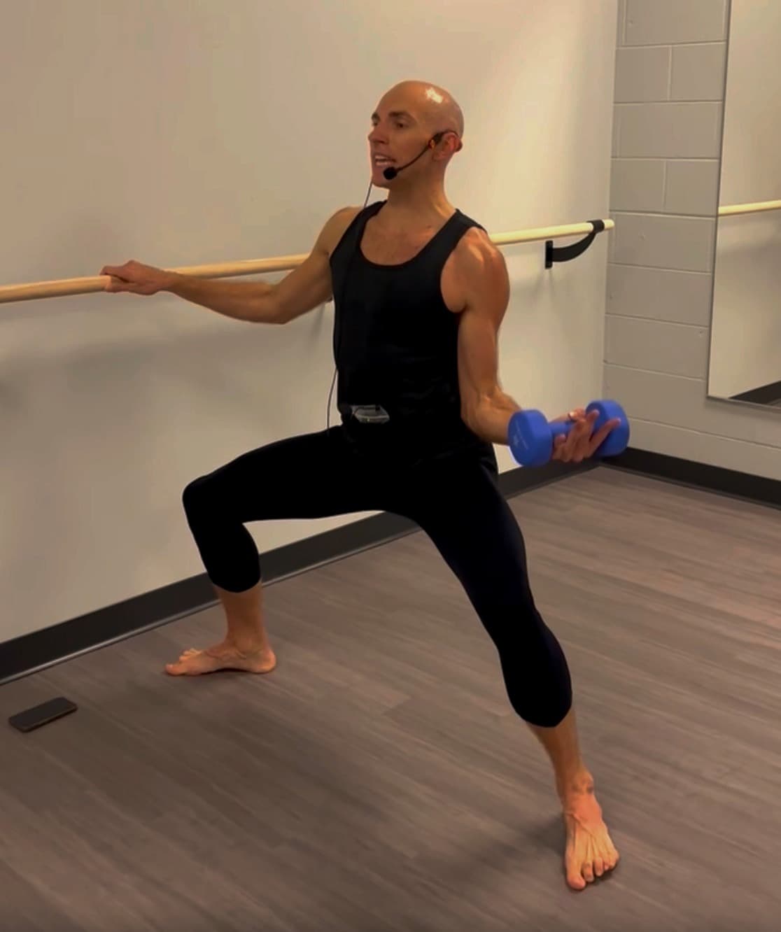 Barre instructor lunging at the barre